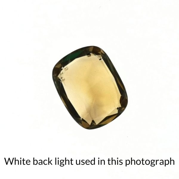 The yellow citrine cushion cut gem is being back-lit with a bright white light to show any inclusions within the gem more clearly.
