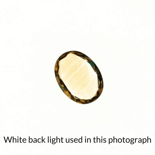The yellow citrine oval gem is being back-lit with a bright white light to show any inclusions within the gem more clearly.
