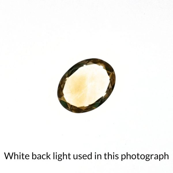 The yellow citrine oval gem is being back-lit with a bright white light to show any inclusions within the gem more clearly.