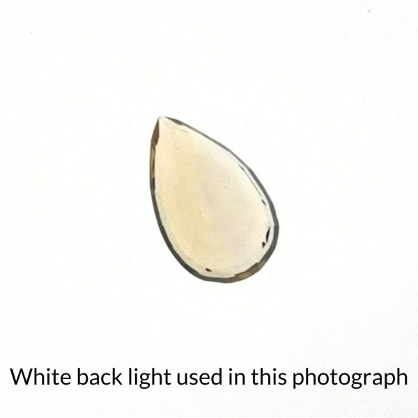 The yellow citrine teardrop gem is being back-lit with a bright white light to show any inclusions within the gem more clearly.