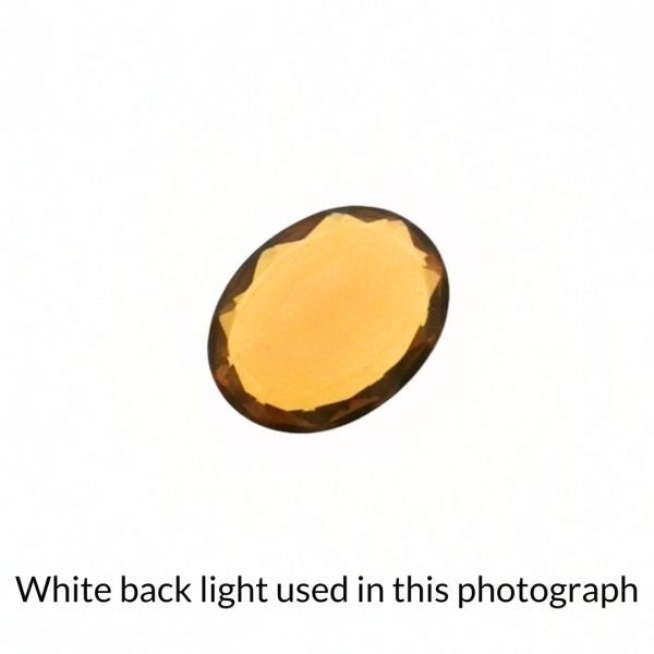 The mandarin orange citrine oval gem is being back-lit with a bright white light to show any inclusions within the gem more clearly.