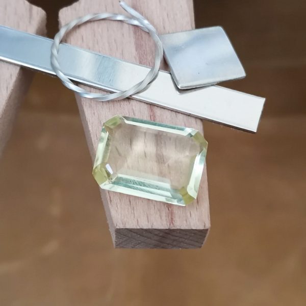 The lemon yellow citrine rectangle displayed on a jewellers bench peg with some sterling silver sheet and wire.