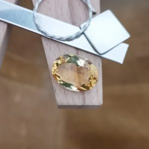 The golden yellow citrine oval displayed on a jewellers bench peg with some sterling silver sheet and wire.