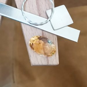 The golden yellow citrine oval displayed on a jewellers bench peg with some sterling silver sheet and wire.