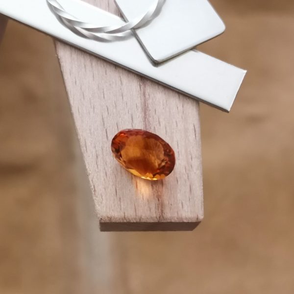 The orange citrine oval displayed on a jewellers bench peg with some sterling silver sheet and wire.