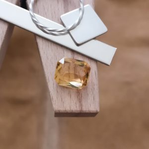 The golden yellow citrine rectangle displayed on a jewellers bench peg with some sterling silver sheet and wire.