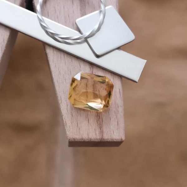 The golden yellow citrine rectangle displayed on a jewellers bench peg with some sterling silver sheet and wire.
