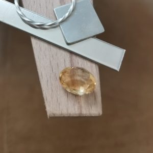 The golden yellow citrine oval displayed on a jewellers bench peg with some sterling silver sheet and wire.