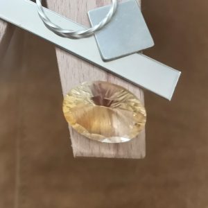 The golden yellow citrine oval displayed on a jewellers bench peg with some sterling silver sheet and wire.