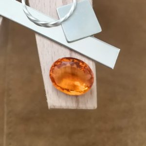 The mandarin orange citrine oval displayed on a jewellers bench peg with some sterling silver sheet and wire.