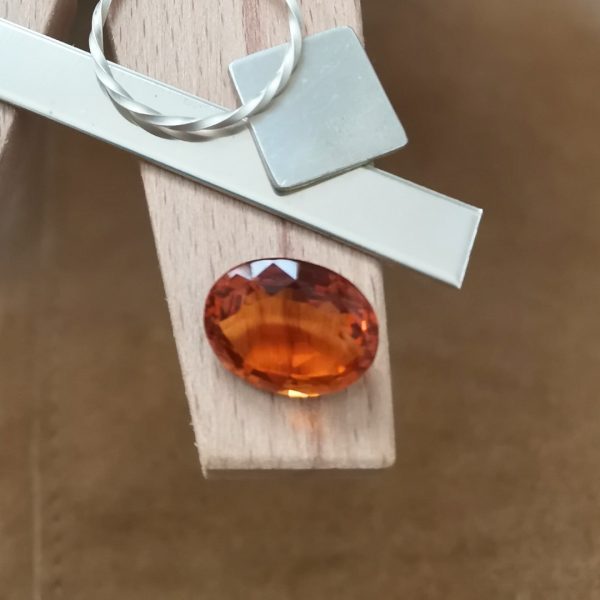 The mandarin citrine oval displayed on a jewellers bench peg with some sterling silver sheet and wire.