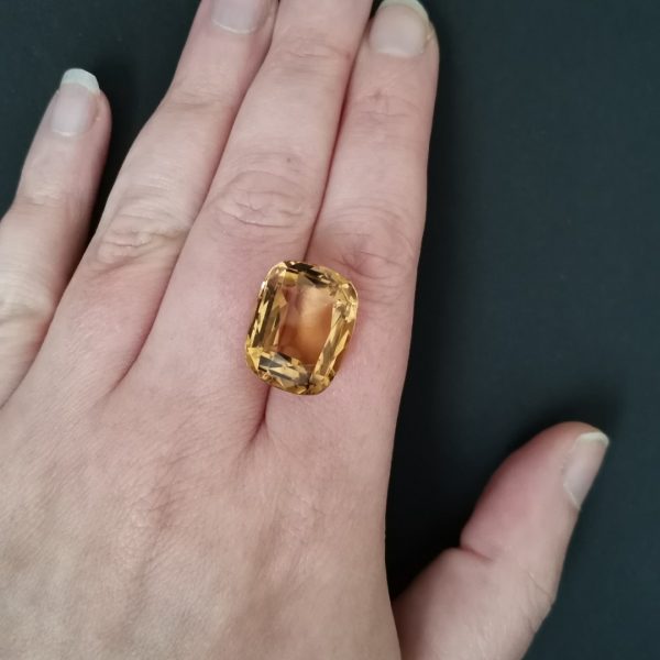 The golden citrine gemstone resting on a hand to give an idea of the gemstone size and colour.