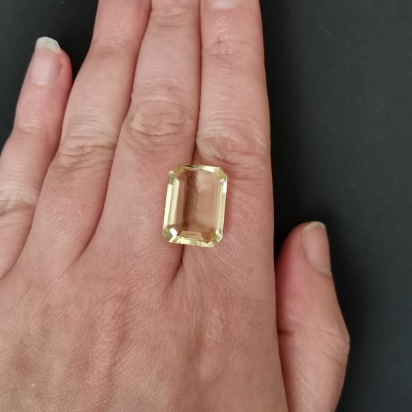 The pale yellow citrine gemstone resting on a hand to give an idea of the gemstones size and colour.