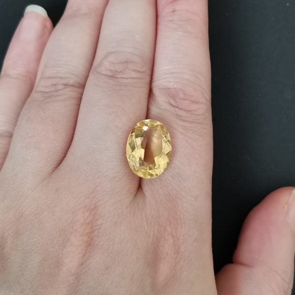 The golden yellow citrine gemstone resting on a hand to give an idea of the gemstones size and colour.