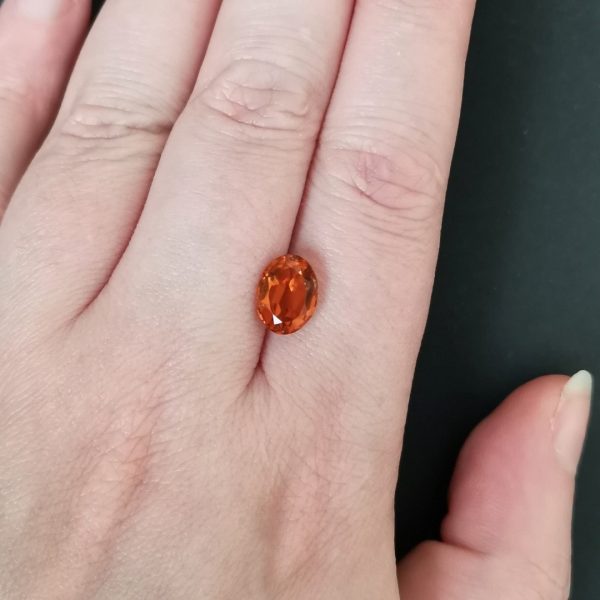 The mandarin citrine gemstone resting on a hand to give an idea of the gemstones size and colour.