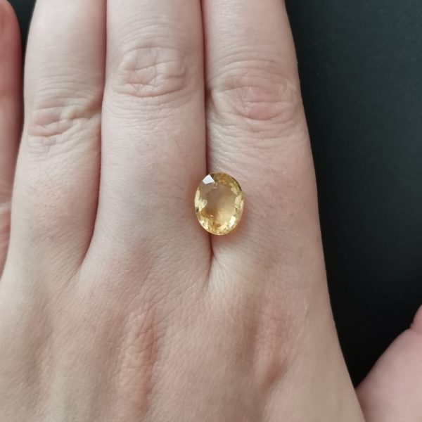 The golden citrine gemstone resting on a hand to give an idea of the gemstone size and colour.