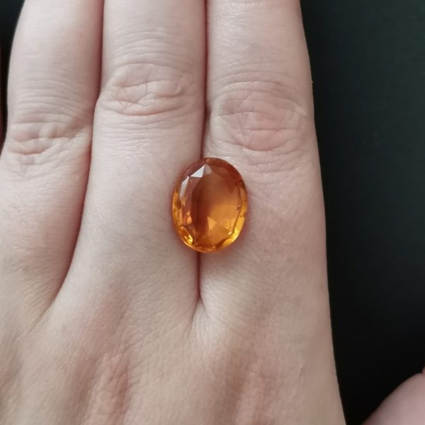 The orange citrine gemstone resting on a hand to give an idea of the gemstone size and colour.