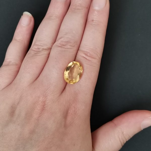 The golden yellow citrine gemstone resting on a hand to give an idea of the gemstone size and colour.