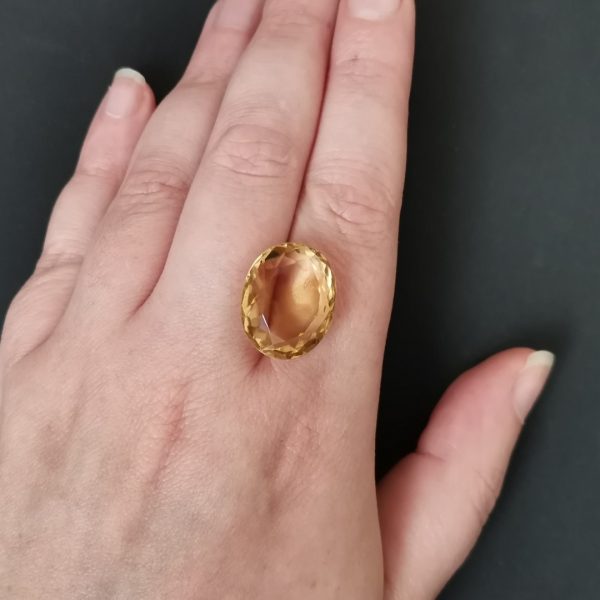 The golden citrine gemstone resting on a hand to give an idea of the gemstone size and colour.