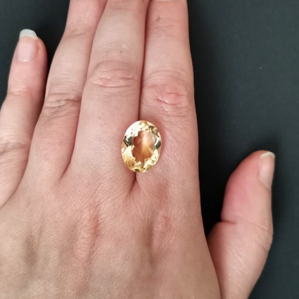The yellow citrine gemstone resting on a hand to give an idea of the gemstone size and colour.