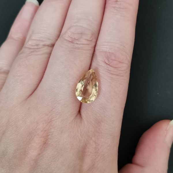 The yellow citrine gemstone resting on a hand to give an idea of the gemstones size and colour.
