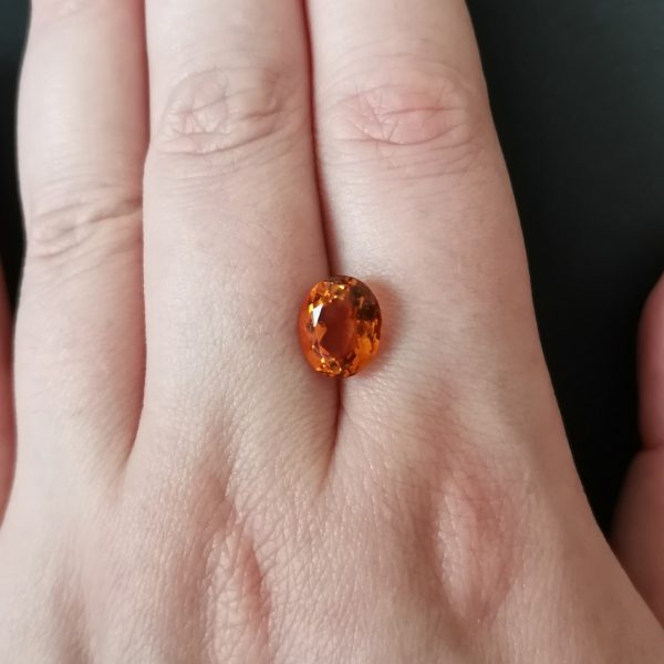 The orange citrine gemstone resting on a hand to give an idea of the gemstone size and colour.