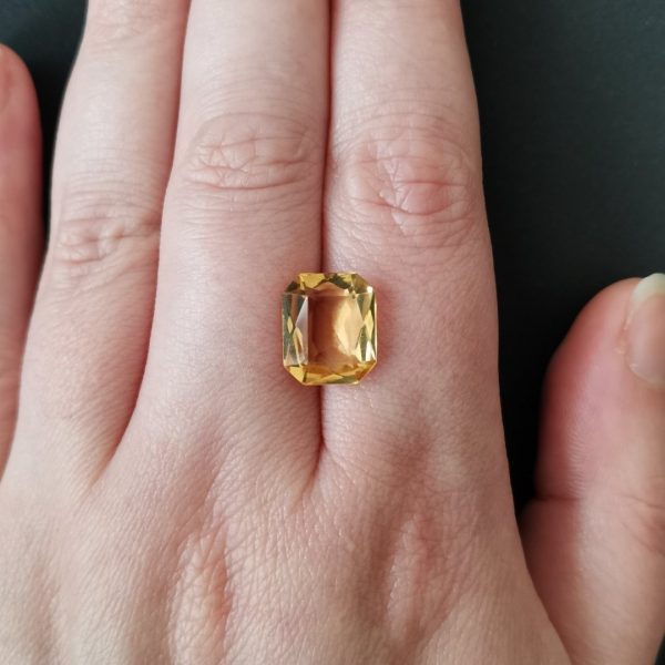 The yellow citrine gemstone resting on a hand to give an idea of the gemstone size and colour.