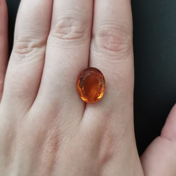 The mandarin citrine gemstone resting on a hand to give an idea of the gemstone size and colour.