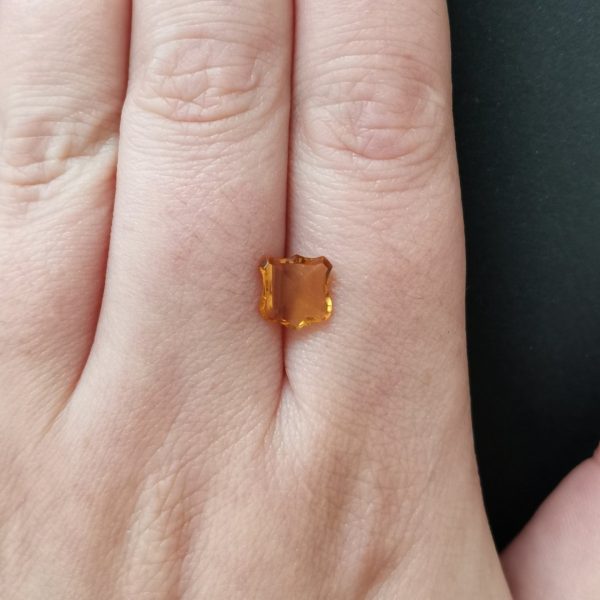 The orange citrine gemstone resting on a hand to give an idea of the gemstone size and colour.