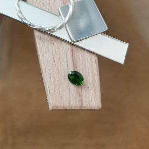 The chrome diopside oval displayed on a jewellers bench peg with some sterling silver sheet and wire.