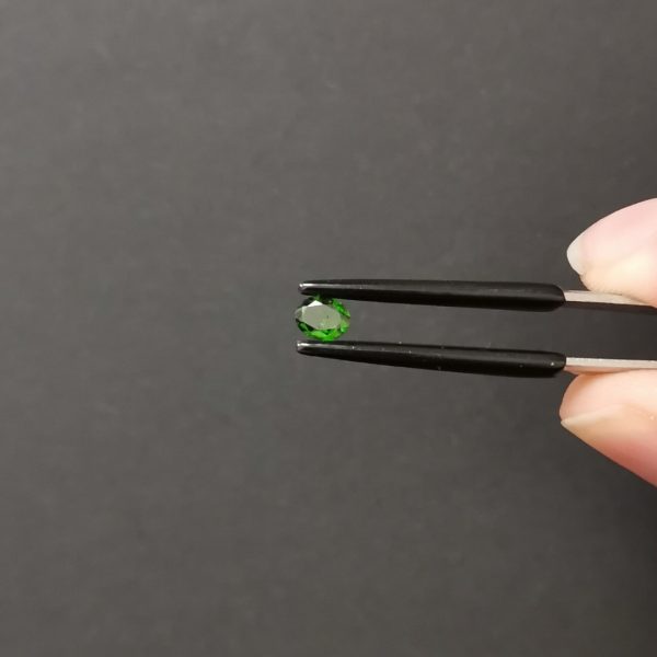 A photo of the crown area of the green diopside against a black background