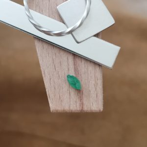 The green emerald marquise displayed on a jewellers bench peg with some sterling silver sheet and wire.