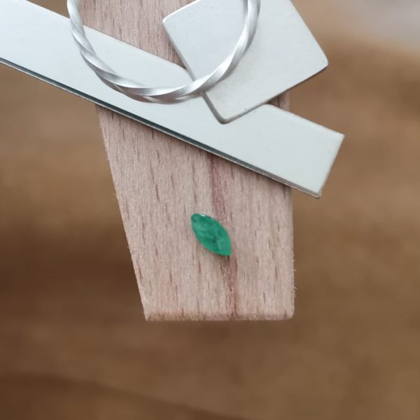 The green emerald marquise displayed on a jewellers bench peg with some sterling silver sheet and wire.