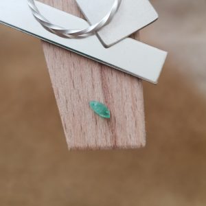 The green emerald marquise displayed on a jewellers bench peg with some sterling silver sheet and wire.