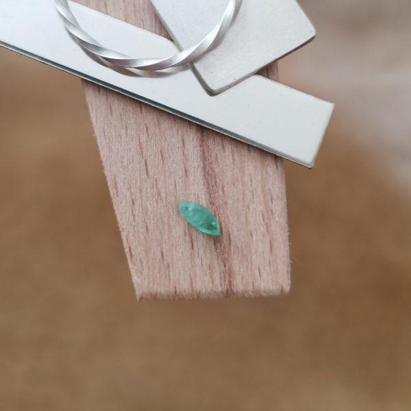 The green emerald marquise displayed on a jewellers bench peg with some sterling silver sheet and wire.