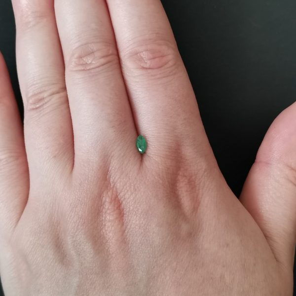 The emerald gemstone resting on a hand to give an idea of the gemstone size and colour.
