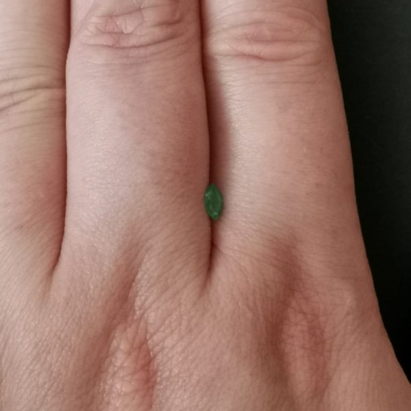 The green emerald gemstone resting on a hand to give an idea of the gemstone size and colour.