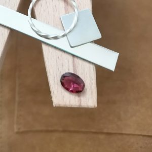 The pink garnet oval displayed on a jewellers bench peg with some sterling silver sheet and wire.