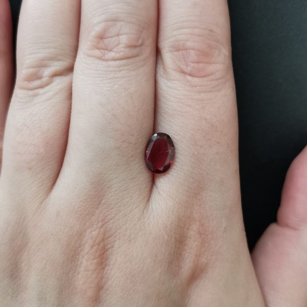 The pink garnet gemstone resting on a hand to give an idea of the gemstone size and colour.