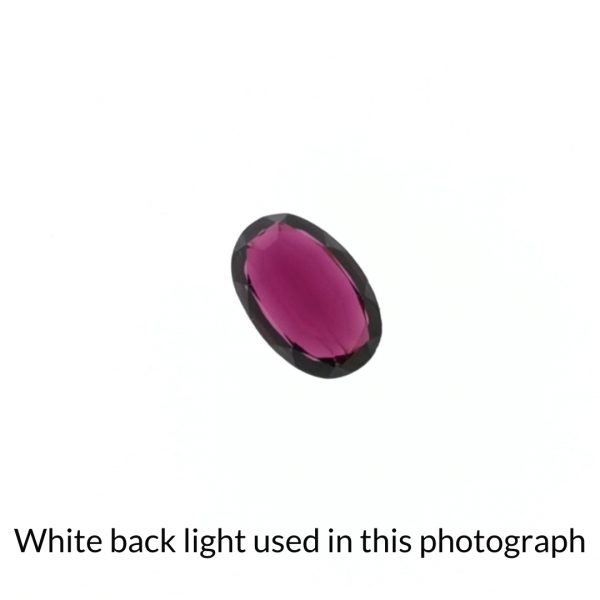 The purple garnet oval gem is being back-lit with a bright white light to show any inclusions within the gem more clearly.