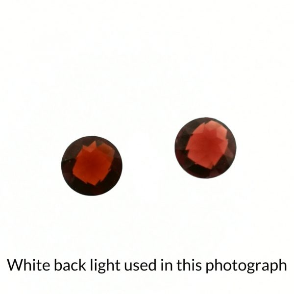 The red garnet round gems are being back-lit with a bright white light to show any inclusions within the gems more clearly.