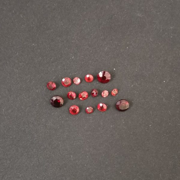 The set of 15 round red garnet gemstones being displayed on a black background