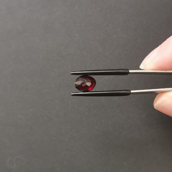 a photo of the pavilion of the dark red garnet oval against a black background