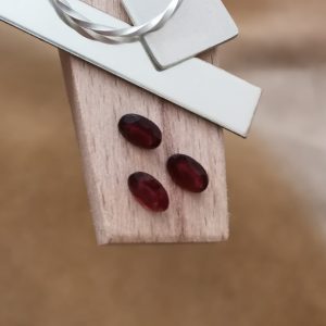 The red garnet ovals displayed on a jewellers bench peg with some sterling silver sheet and wire.