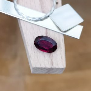 The purple garnet oval displayed on a jewellers bench peg with some sterling silver sheet and wire.