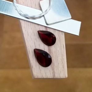 This pair of red garnet teardrops are displayed on a jewellers bench peg with some sterling silver sheet and wire.