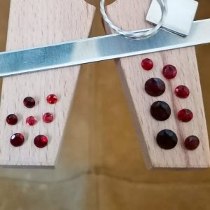 The round red garnet bundle displayed on a jewellers bench peg with some sterling silver sheet and wire.