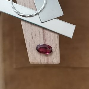 The pink garnet oval displayed on a jewellers bench peg with some sterling silver sheet and wire.