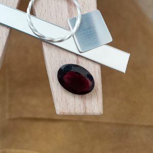 The red garnet oval displayed on a jewellers bench peg with some sterling silver sheet and wire.