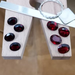 The bundle of red garnet ovals displayed on a jewellers bench peg with some sterling silver sheet and wire.